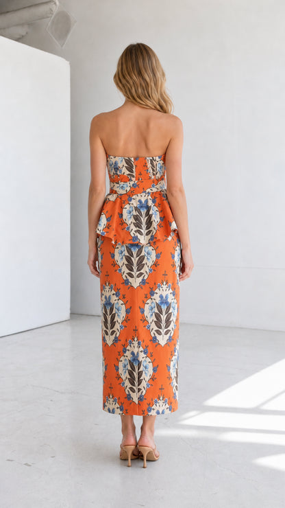 Back view of model in orange strapless floral midi dress