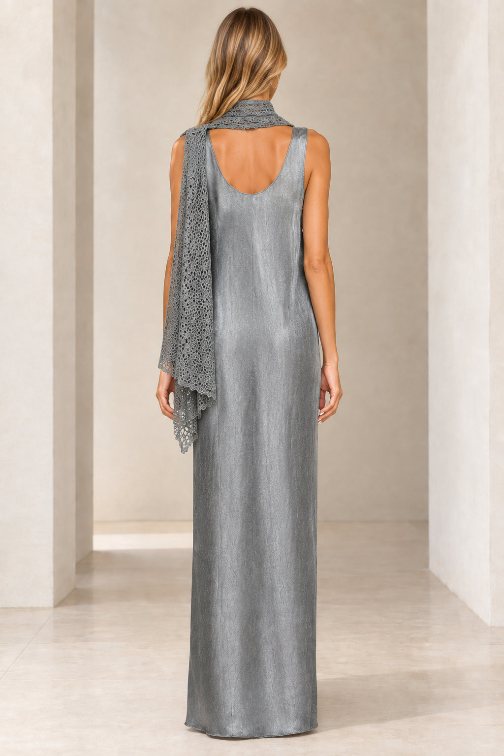 Back view of woman wearing silver shimmer maxi dress showing open back and draped scarf