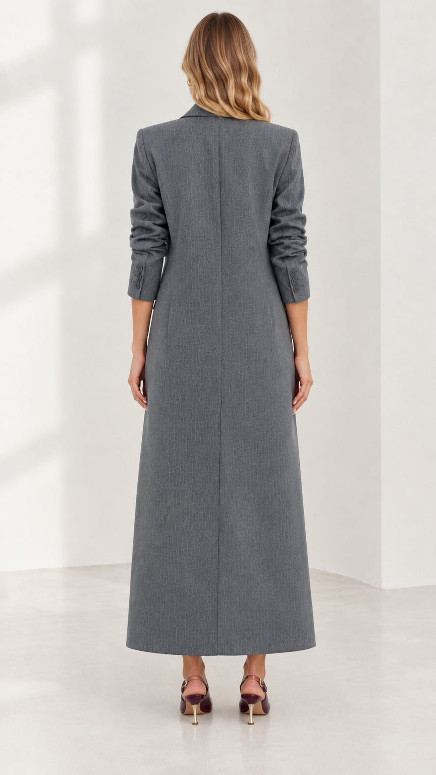 Back view of woman wearing structured grey maxi coat showing long clean hemline