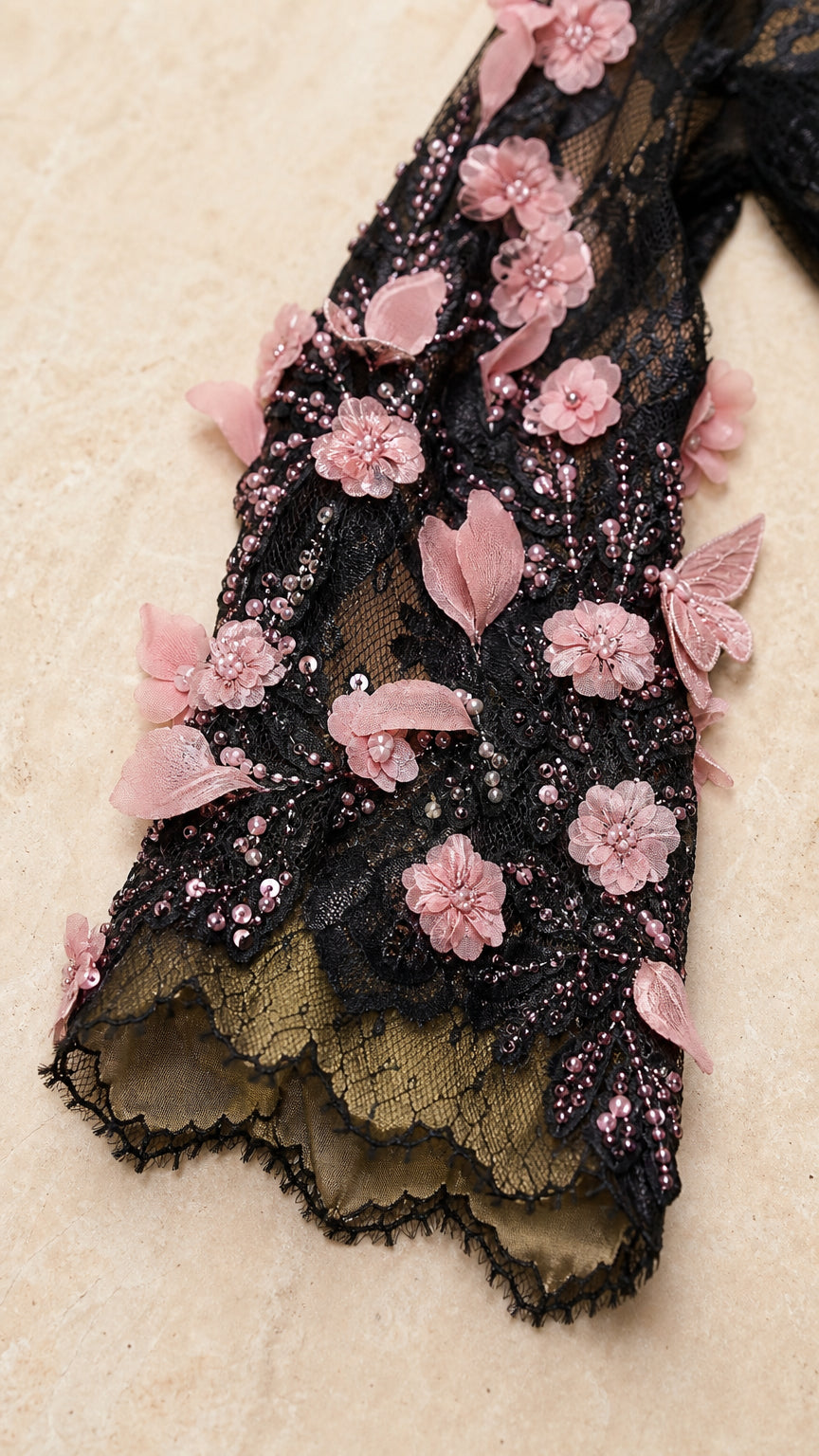 Close-up detail of sheer lace sleeve with 3D pink flower appliqués, beading, and scalloped cuff