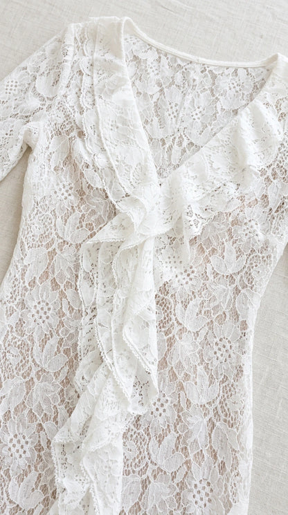 Close-up detail of white floral lace texture and neckline ruffles