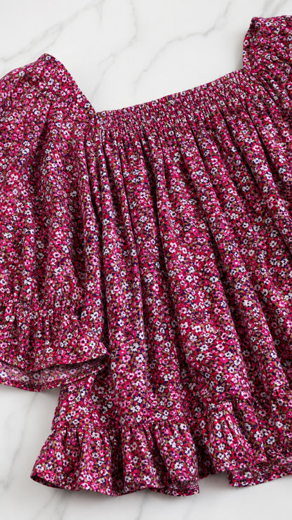 Close-up detail of shirred neckline and ruffled sleeve of magenta ditsy floral top