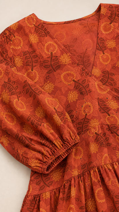 Close-up detail of rust floral fabric, V-neckline, and elastic cuff sleeve