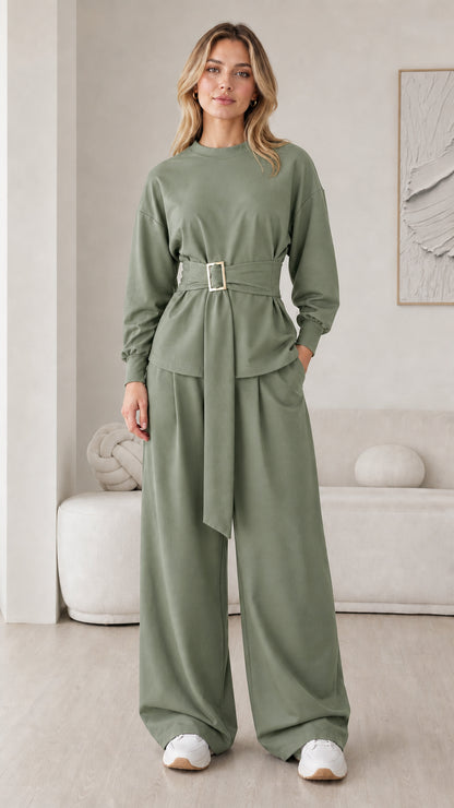 Model wearing sage green matching two-piece belted top and wide leg pants set