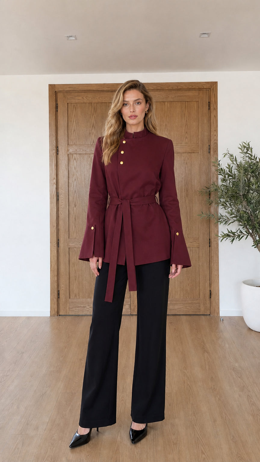 Model wearing burgundy red asymmetrical belted jacket