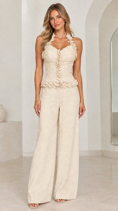 Front view of model wearing Champagne cream ruffle halter wide-leg jumpsuit